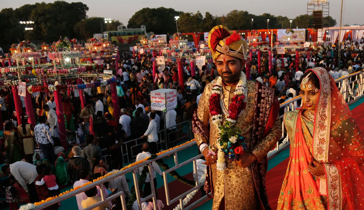 Sepasang pengantin berjalan bersama saat nikah massal di Surat, India, Minggu (23/12). Sebanyak 261 pasangan mengikuti acara nikah massal kali ini. (AP/Ajit Solanki)