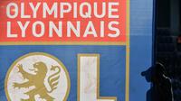 Tampak seorang fans melewati logo tim Olympique Lyonnais atau yang dikenal dengan Lyon. (Rémy GABALDA / AFP)
