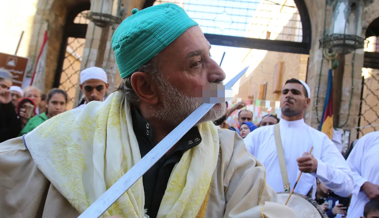 Pria Muslim Sufi Lebanon menggesekan pedang di mulutnya saat perayaan Maulid Nabi Muhammad SAW di Sidon, Lebanon (30/11). Mereka merayakan hari kelahiran Nabi Muhammad SAW yang jatuh pada tanggal 12 Rabiul Awal. (AFP Photo/Mahmoud Zayyat)