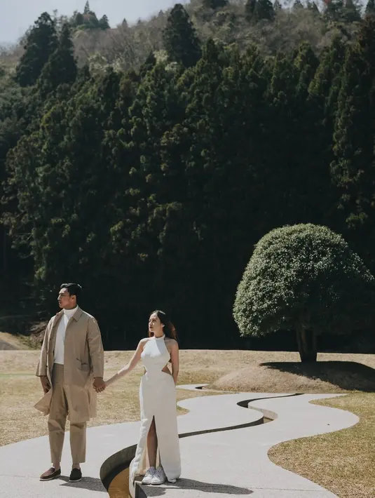 Pemotretan yang tak tanggung-tanggung, Ibrahim dengan turtleneck putih ditumpuknya mengenakan trench coat cokelat yang serasi dengan celana panjang dan alas kakinya. Sedangkan Salshabilla tampil manis mengenakan halter-neck dress putih dengan detail cut outs di bagian pinggang kanan-kiri dan high slit di tengah. [Foto: Instagram/ibrhmrsyd]