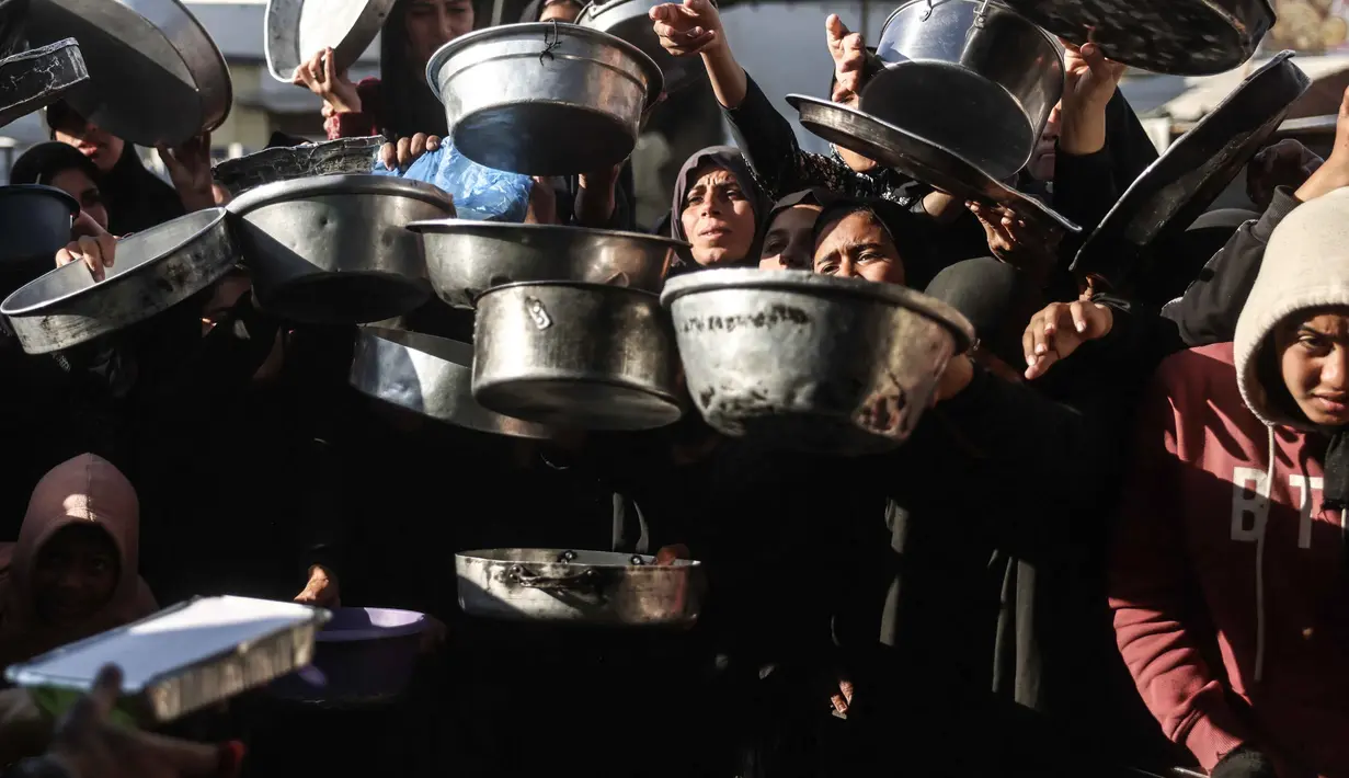 Sebelumnya, militer Israel menutup semua akses ke Gaza pada Sabtu (28/2/2026) setelah mengumumkan serangan udara terhadap Iran yang dilakukan bersama dengan Amerika Serikat. Tampak dalam foto, warga Palestina yang mengungsi berebut untuk makanan di Khan Younis, selatan Jalur Gaza pada Jumat 6 Maret 2026. (Bashar Taleb/AFP)