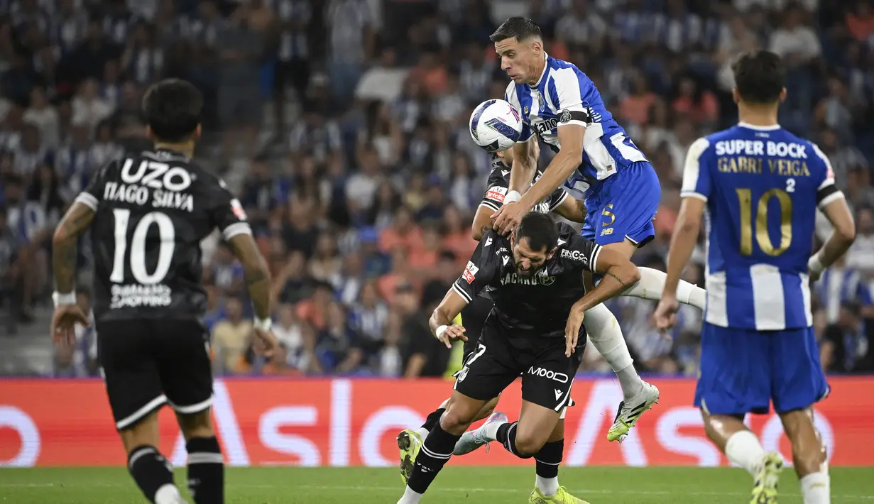 Pemain FC Porto, Jan Bednarek (atas) berebut bola dengan pemain Vitoria Guimaraes, Nelson Oliveira dalam laga Liga Portugal 2025/2026 di Estadio Do Dragao, Porto, Portugal, Senin (11/08/2025) waktu setempat. (AFP/Miguel Riopa)