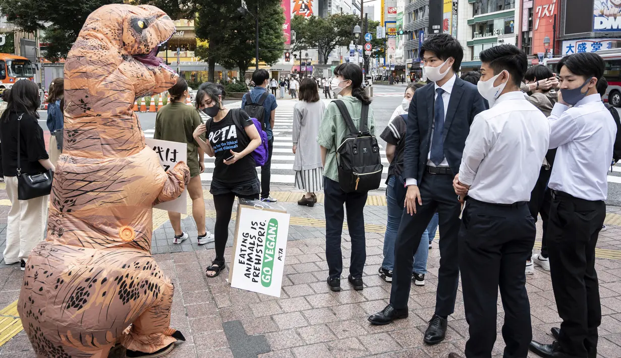 Aktivis kelompok hak hewan PETA mendesak orang untuk menjadi vegan selama protes di Tokyo, Jepang, Rabu (6/10/2021). Dalam aksinya, para aktivis mengenakan kostum dinosaurus. (CHARLY TRIBALLEAU/AFP)