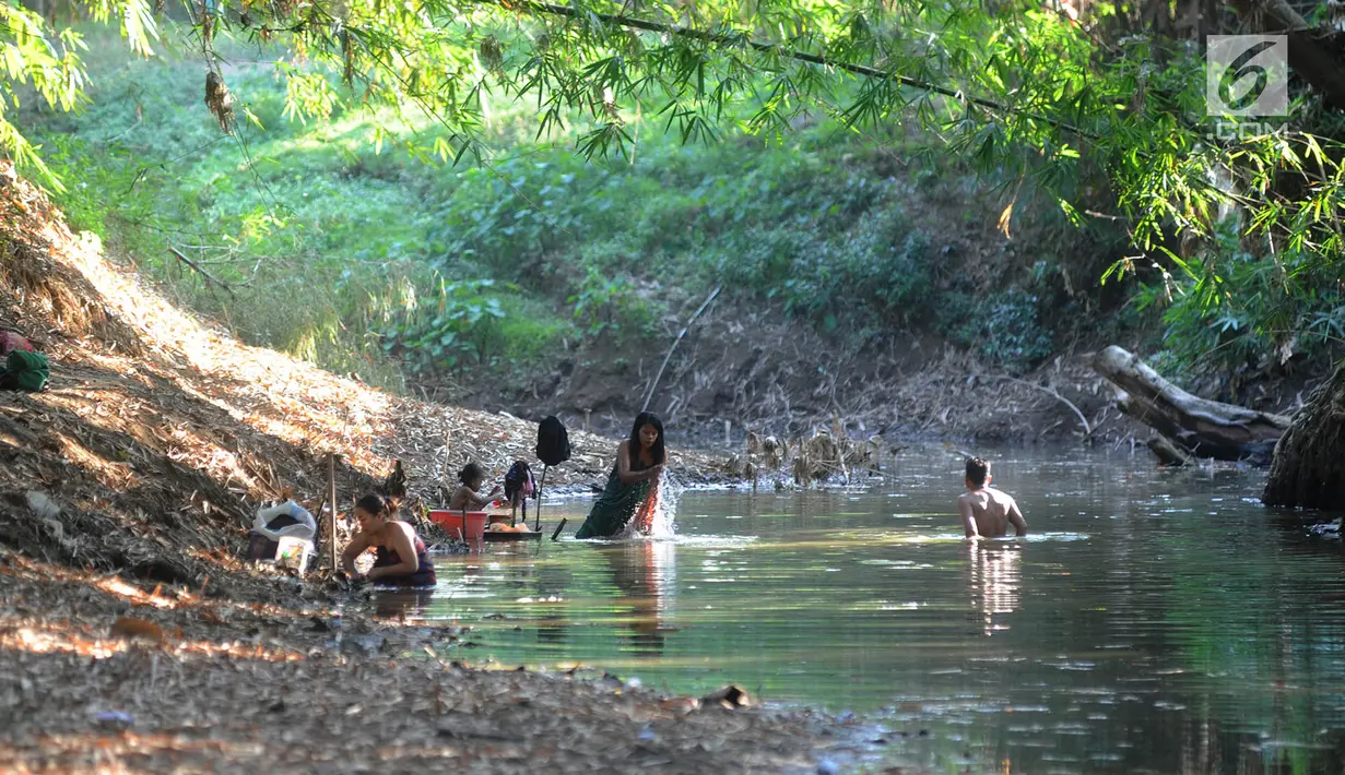 Warga mengambil air dari lubang pada aliran Sungai Cihoe untuk memenuhi kebutuhan sehari-hari termasuk air minum di kawasan Ridogalih, Cibarusah, Bekasi, Minggu (7/7/2019). Sudah lebih dari dua bulan, warga memanfaatkan sisa aliran sungai yang kotor akibat musim kemarau. (merdeka.com/Arie Basuki)
