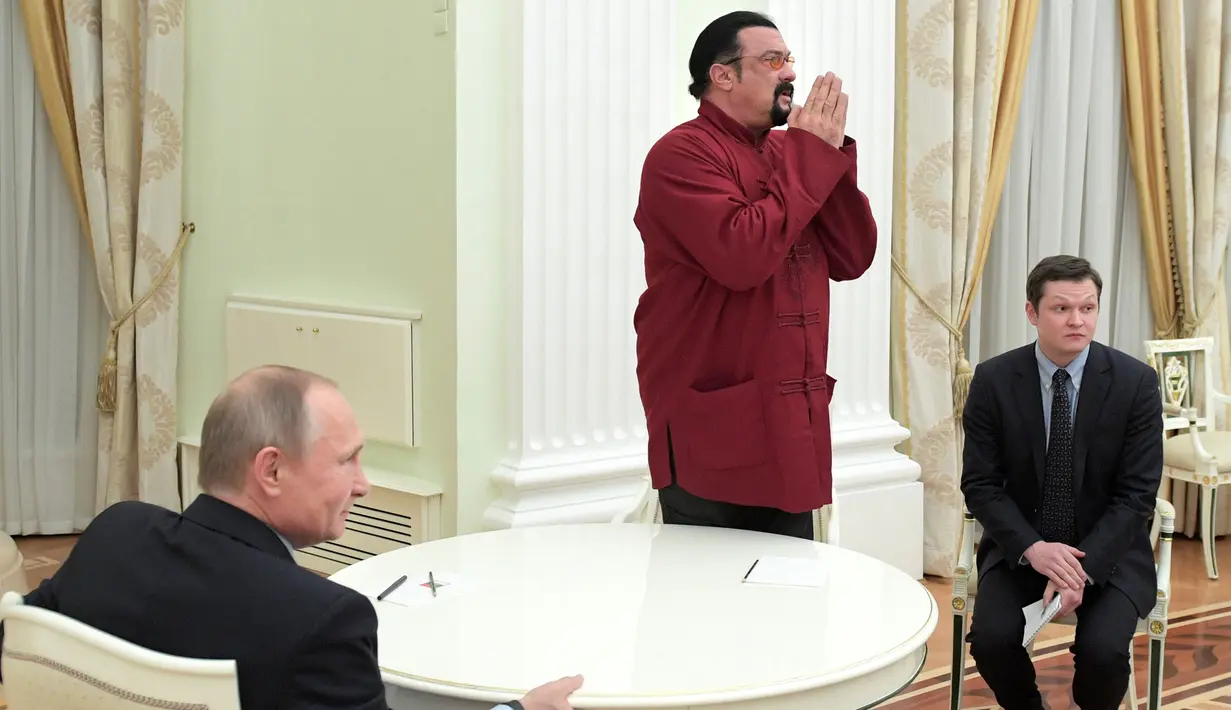 Aktor AS, Steven Seagal menyapa awak media saat bertemu dengan Presiden Rusia Vladimir Putin untuk menandatangani paspor miliknya berkenegaraan Rusia di Kremlin di Moskow, Rusia, (25/11). (Sputnik/Kremlin/Alexei Druzhinin via REUTERS)
