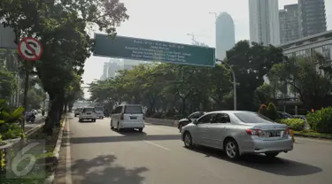 Kendaraan melaju di bawah papan petunjuk penerapan sistem ganjil genap di Bundaran Senayan, Jakarta, Rabu (27/7). Kebijakan pembatasan kendaraan dengan penerapan pelat ganjil genap dimulai hari ini hingga tanggal 26 Agustus. (Liputan6.com/Gempur M Surya)