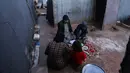 Pengungsi Suriah berkumpul di depan tenda untuk berbuka puasa dengan makanan yang didistribusikan organisasi amal lokal selama bulan suci Ramadhan, di kamp pengungsi di pinggiran kota Dana yang dikuasai pemberontak, timur perbatasan Turki-Suriah di Idlib (3/4/2022). (AFP/Aaref Watad)