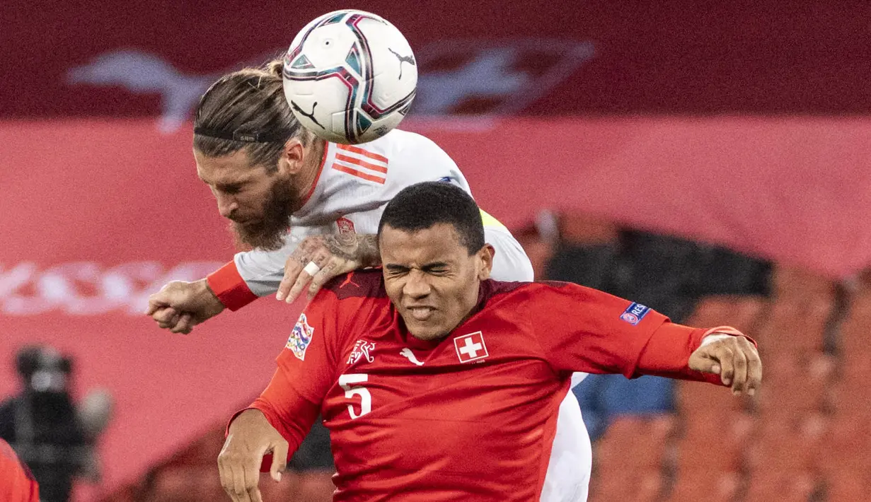 Bek Spanyol, Sergio Ramos, duel udara dengan pemain Swiss, Manuel Akanji, pada laga UEFA Nations League di Stadion St. Jakob-Park, Minggu (15/11/2020). Kedua tim bermain imbang 1-1. (Georgios Kefalas/Keystone via AP)