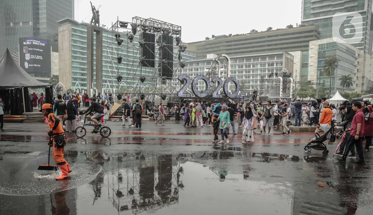 Petugas Penanganan Prasaran dan Sarana Umum (PPSU) membersihkan genangan air saat car free day (CFD) di kawasan Bundaran HI, Jakarta, Minggu (29/12/2019). Pembersihan genangan air dilakukan agar warga yang sedang berolahraga di kawasan tersebut nyaman. (Liputan6.com/Faizal Fanani)