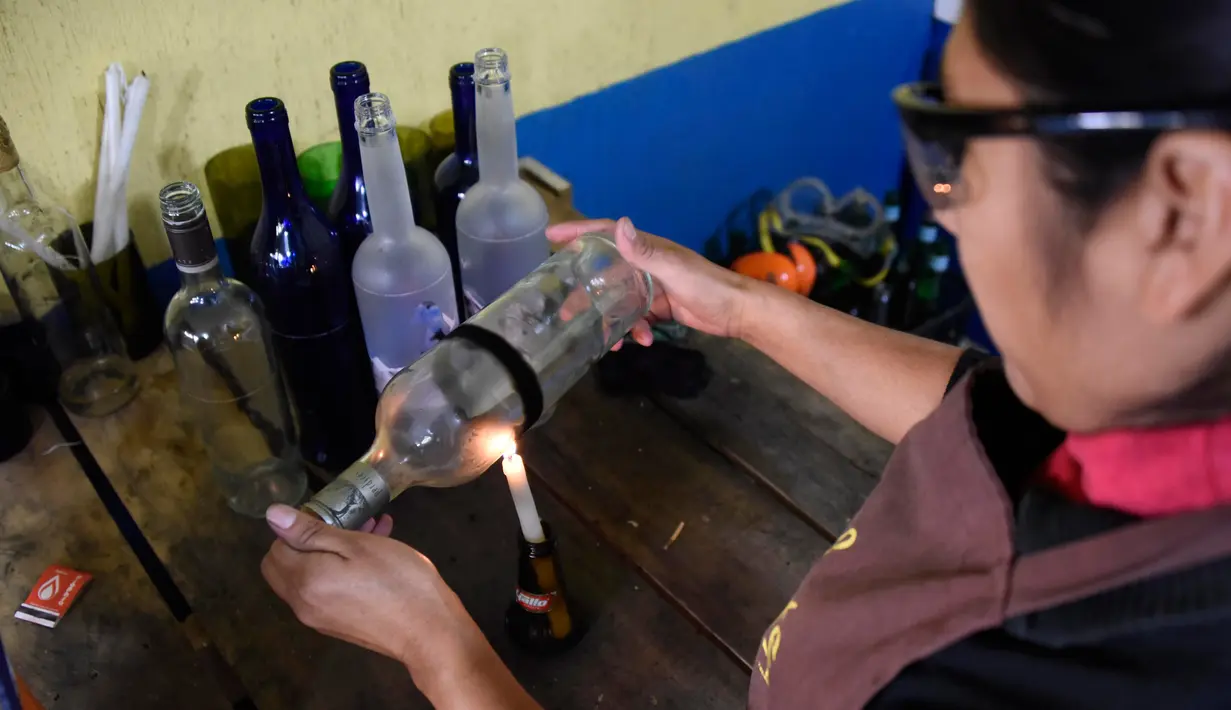 Salah satu proses jelang pemotongan botol di Guatemala (12/2). Dengan peralatan sederhana, mereka menyulap botol-botol tersebut menjadi gelas dan vas yang laris dijual di supermarket. (AFP PHOTO/JOHAN Ordonez)