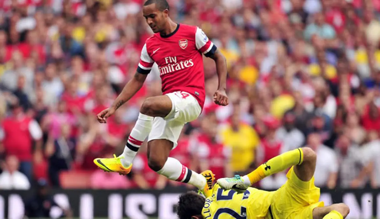 Striker Arsenal Theo Walcott (kiri) melompat menghindari benturan dengan kiper Tottenham Hotspur Hugo Lloris (kanan) pada pertandingan sepak bola Liga Utama Inggris antara Arsenal dan Tottenham Hotspur di Stadion Emirates di London (01/09/2013). (AFP/Glyn