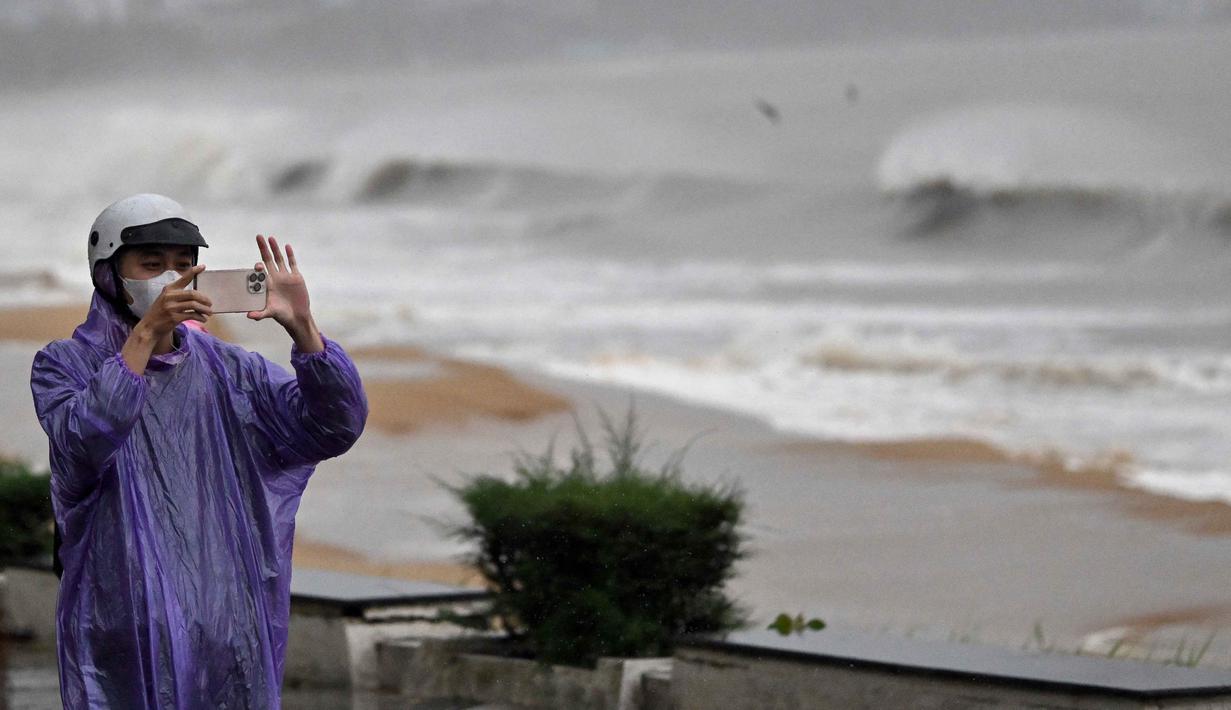 Badai juga berpotensi menyebabkan banjir di daerah dataran rendah. Tampak dalam foto, seorang warga merekam dengan ponselnya saat ombak menghantam Pantai Quy Nhon menjelang kedatangan Topan Kalmaegi di Provinsi Gia Lai, Vietnam Tengah, pada 6 November 2025. (NHAC NGUYEN/AFP)