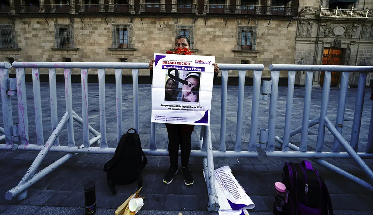 Maria de la Luz Flores memegang poster putrinya Guadalupe Morales Flores yang hilang pada 7 September 2020 dan ditemukan 29 Maret 2021 saat protes di luar Istana Nasional menuntut jawaban dari pemerintah tentang orang-orang hilang di Mexico City, Meksiko, 13 Desember 2021. (AP Photo/Marco Ugarte)