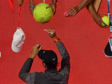 Petenis asal Spanyol, Rafael Nadal memberikan tanda tangan kepada penggemarnya setelah menang atas Matthew Ebden dari Australia pada pertandingan tunggal putra turnamen Australia Terbuka di Melbourne, Rabu (16/1). (Photo by Peter PARKS / AFP)