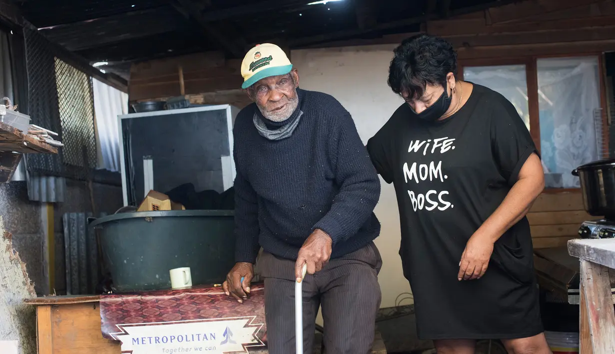 Fredie Blom (kiri) dibantu salah seorang putri dari istrinya ketika merayakan ulang tahun ke 116 di rumahnya di Delft, dekat Cape Town, 8 Mei 2020. Menurut 'Oupa' (kakek) Fredie dan kartu identitasnya, ia lahir pada tahun 1904 yang menjadikannya salah satu pria tertua di dunia. (RODGER BOSCH/AFP)