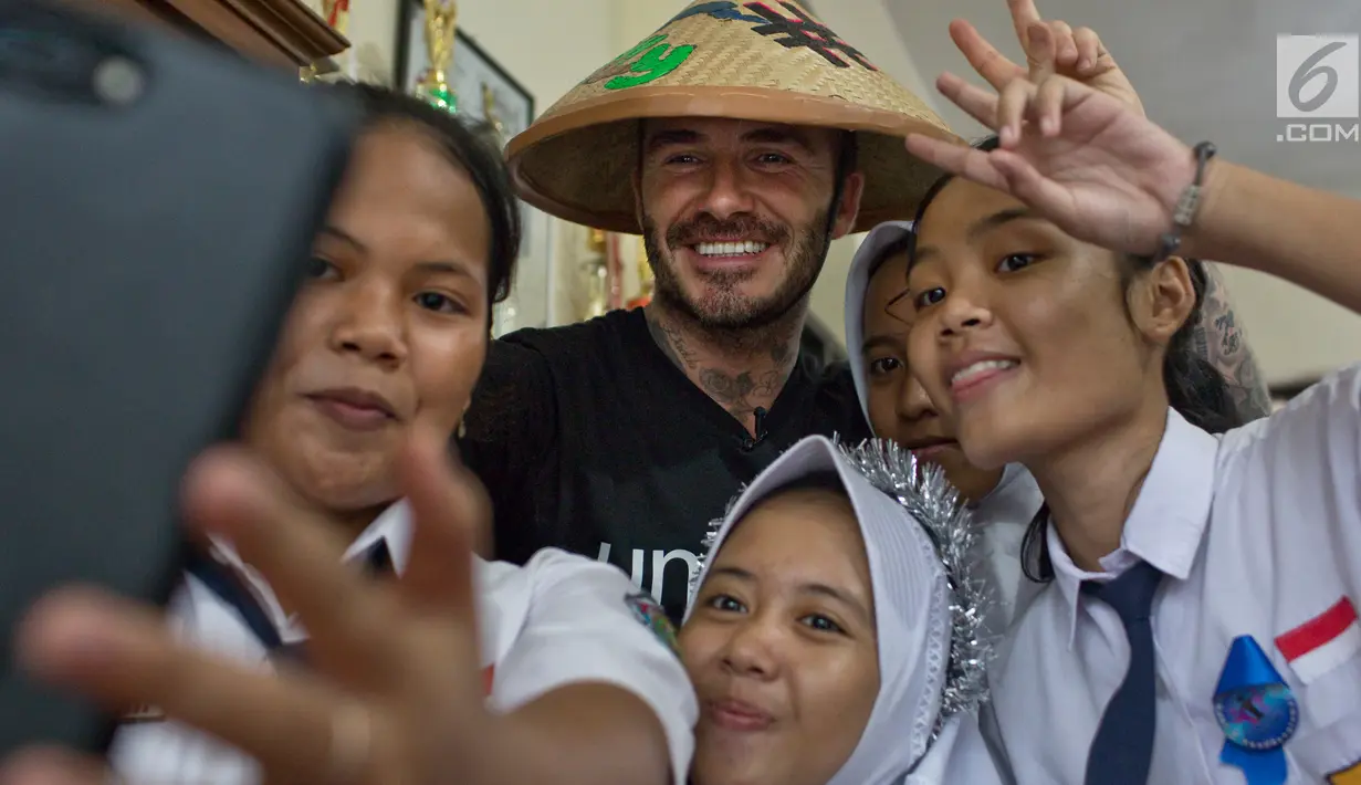 Duta Kehormatan UNICEF, David Beckham berswafoto dengan siswi SMPN 17 Semarang, Sripun dan rekan-rekannya di Jawa Tengah, Rabu (28/3). Kedatangan Beckham di Semarang merupakan rangkaian kegiatan amal yang dilakukannya bersama UNICEF. (Liputan6.com/UNICEF)