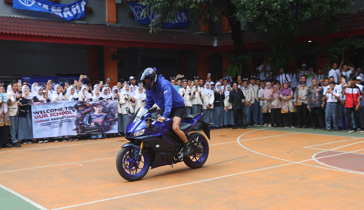 Kedatangan Toprak Razgatlioglu berdekatan dengan tes shakedown di Sirkuit Sepang, Malaysia, pada 29-31 Januari 2026 nanti. Tampak dalam foto, pembalap rookie Prima Pramac Racing, Toprak Razgatlioglu saat beraksi di depan siswa/siswi SMK Negeri 39, kawasan Cempaka Putih, Jakarta Pusat, Selasa (20/1/2026). (Bola.com/M Iqbal Ichsan)