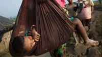 Seorang anak digendong ibunya saat mengungsi ke perbatasan Bangladesh di daerah Teknaf Cox's Bazar (5/9). Belasan ribu warga Rohingya melarikan diri ke Bangladesh, sejak bentrokan kembali pecah di Rakhine.(AP Photo/Bernat Armangue)