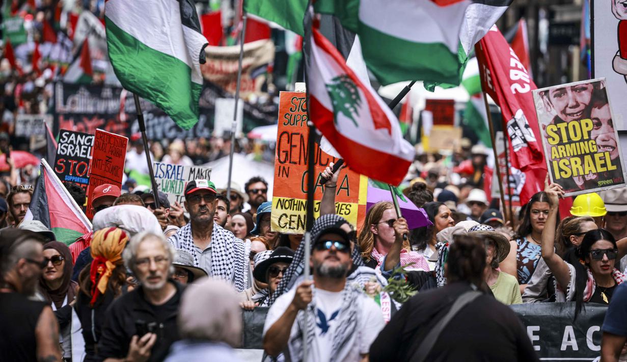 Para demonstran pro-Palestina membawa bendera, spanduk, dan plakat saat mereka berbaris berunjuk rasa di jalanan kota Sydney, Australia, Minggu 22 Februari 2026. Ribuan demonstran pro-Palestina kembali berkumpul memenuhi salah satu ruas jalan di Sydney, Australia. (DAVID GRAY/AFP)