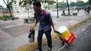 Seorang penjual kopi berjalan saat terjadi bentrokan antara pasukan keamanan dan penentang Presiden Nicolas Maduro di Caracas, Venezuela, (26/3). (AP Photo / Ariana Cubillos)