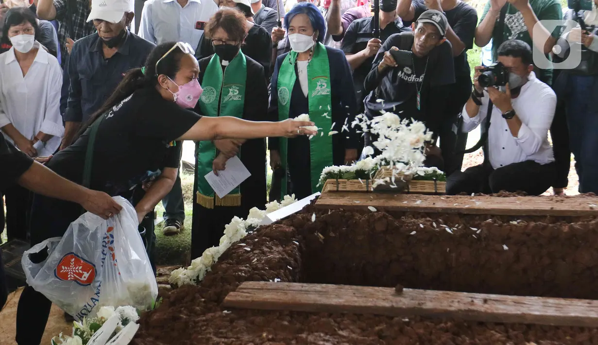 Keluarga menaburkan bunga ke dalam liang lahat musisi legendaris Bob Tutupoly saat pemakaman di Tempat Pemakaman Umum (TPU) Tanah Kusir, Jakarta, Kamis (7/7/2022). Almarhum Bob Tutupoly meninggal setelah mengalami stroke dan penyakit penyerta. (Liputan6.com/Herman Zakharia)