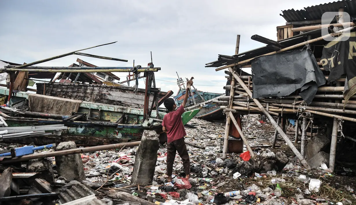 Aktivitas warga dekat tumpukan sampah yang terbawa arus laut di permukiman nelayan Cilincing, Jakarta Utara, Rabu (8/6/2022). Jumlah sampah di laut Nusantara secara keseluruhan diperkirakan sudah mencapai 5,75 juta ton. (merdeka.com/Iqbal S. Nugroho)