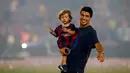 Penyerang Barcelona, Luis Suarez bersama anaknya saat parade kemenangan di stadion Camp Nou, Spanyol (7/6/2015). Barcelona untuk kelima kalinya meraih piala liga Champions usai mengalahkan Juventus 3-1 di Stadion Olympic. (REUTERS/Albert Gea)