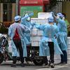 Pekerja yang mengenakan alat pelindung diri menumpuk kotak ke atas gerobak untuk dikirim saat perberlakuan lockdown karena virus corona COVID-19 di Distrik Jing'an, Shanghai, China, Rabu (18/5/2022). (Hector RETAMAL/AFP)
