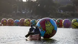 Relawan mengangkut bola raksasa ke danau MacArthur Park selama pameran "Spheres" di Los Angeles, California, AS (21/8/2015). Acara ini menampilkan sekitar 3.000 bola raksasa yang dihias oleh para relawan. (REUTERS/Mario Anzuoni)