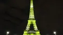 Pengunjung berjalan di sekitar Menara Eiffel yang diterangi huruf '300 juta terima kasih' di Paris, Kamis (28/9). 1.500 pengunjung pertama diperbolehkan masuk gratis untuk menari di set DJ lantai pertama menara pada pukul 18.00-23.00. (LUDOVIC MARIN/AFP)