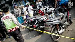 Aparat kepolisian memasang garis polisi di lokasi ledakan bom Kampung Melayu, Kamis (25/5). Lokasi terjadinya ledakan bom dipadati warga untuk berfoto dan melihat langsung peristiwa yang menewaskan tiga polisi tersebut. (Liputan6.com/Faizal Fanani)