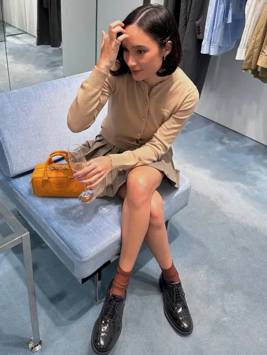 Gaya high school yang manis ala Tatjana Saphira. Ia mengenakan sweater cokelat muda, dipadu padankan dengan pleated mini skirt bernuansa kecokelatan yang senada. [Foto: Instagram/tatjanasaphira]