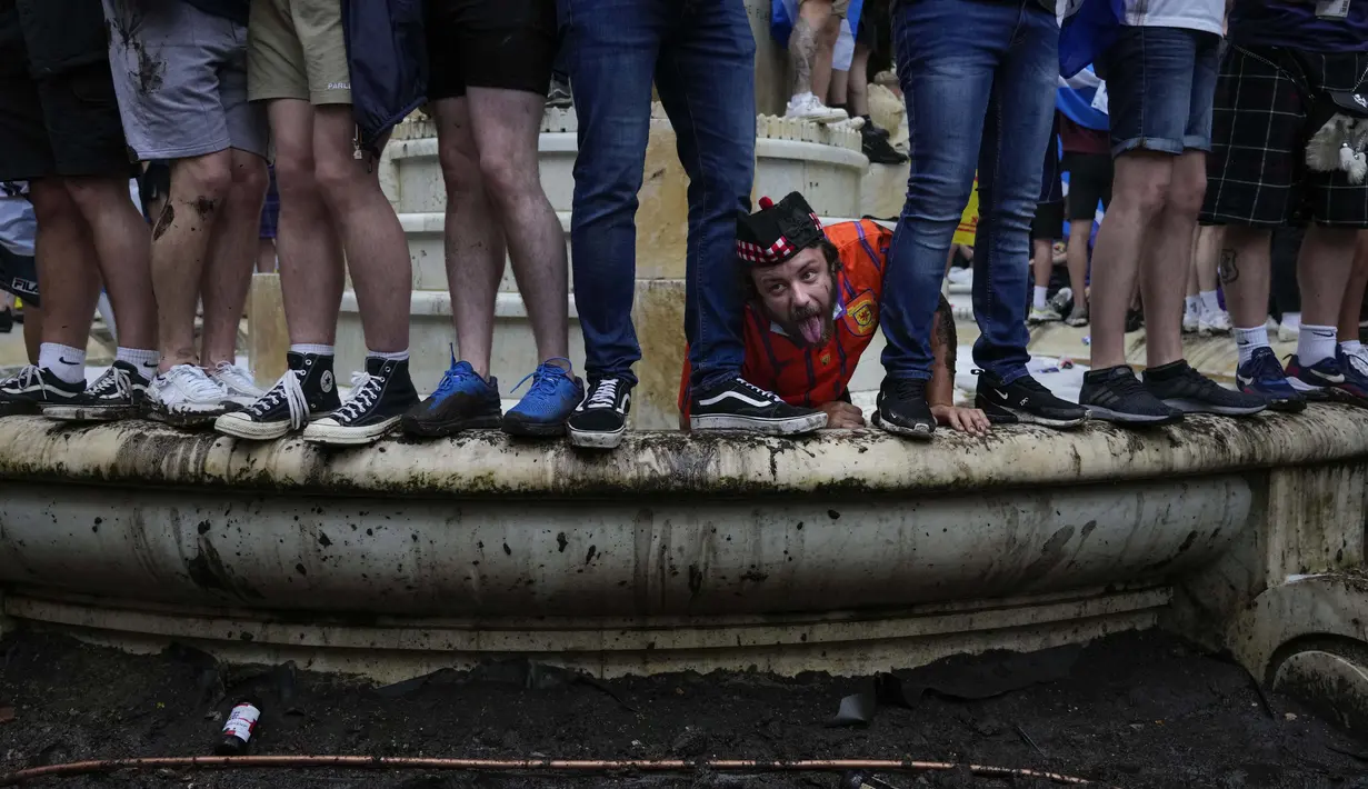 Suporter Skotlandia memanjat patung William Shakespeare di Leicester Square sebelum pertandingan grup D Euro 2020 antara Inggris melawan Skotlandia, di London, Jumat, (18/6/2021). (Foto: AP/Kirsty Wigglesworth)