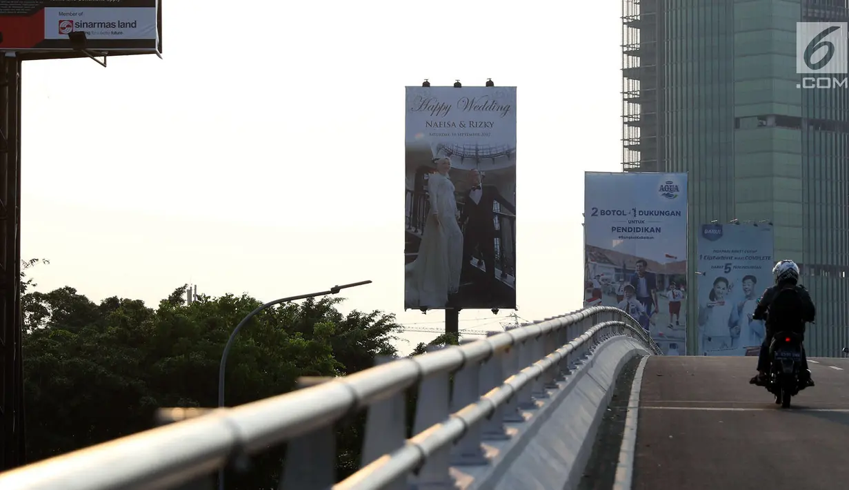 Pengendara motor melintasi sebuah billboard ucapan pernikahan di jalan layang Tanjung Barat, Jagakarsa, Jakarta, Kamis (21/9). Papan iklan itu memuat satu pasangan bernama Nafisa dan Rizky. (Liputan6.com/Immanuel Antonius)