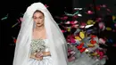 Supermodel Gigi Hadid berjalan di runway mengenakan gaun rumah mode Moschino untuk koleksi SS19 selama gelaran fashion week di Milan, Italia, Kamis (20/9). Gigi Hadid mencuri perhatian publik dengan tampil bak seorang pengantin. (AP/Antonio Calanni)