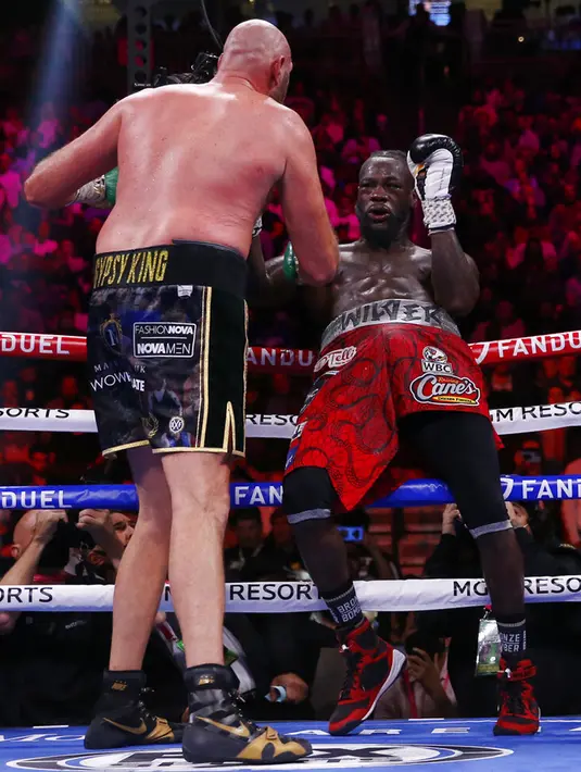 Tyson Fury (kiri) memukul Deontay Wilder pada pertandingan tinju kelas berat WBC di T-Mobile Arena, Las Vegas, Nevada, Amerika Serikat, 9 Oktober 2021. Tyson Fury mempertahankan sabuk juara dunia tinju kelas berat WBC usai mengalahkan Deontay Wilder pada ronde 11. (AP Photo/Chase Stevens)