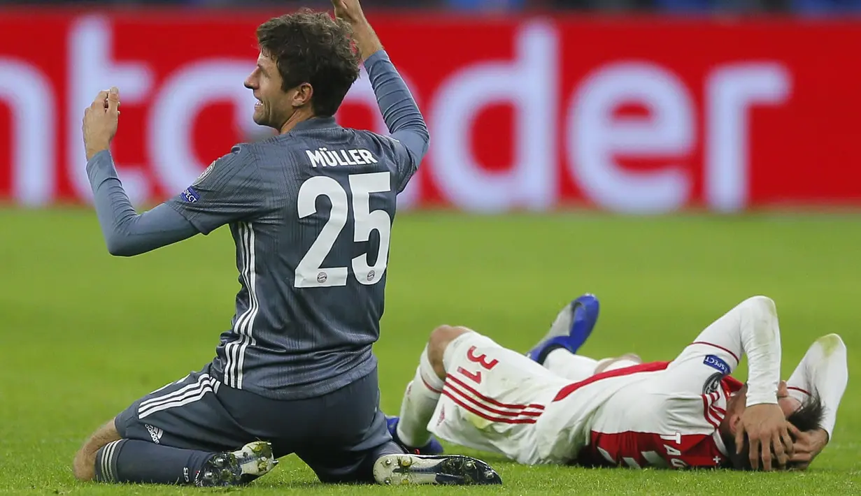 Bek Ajax Amsterdam, Nicolas Tagliafico, memegang kepala usai ditendang gelandang Bayern Munchen, Thomas Mueller, pada laga Liga Champions di Johan Cruyff Arena, Amsterdam, Rabu (12/12). Kedua tim bermain imbang 3-3. (AP/Peter Dejong)