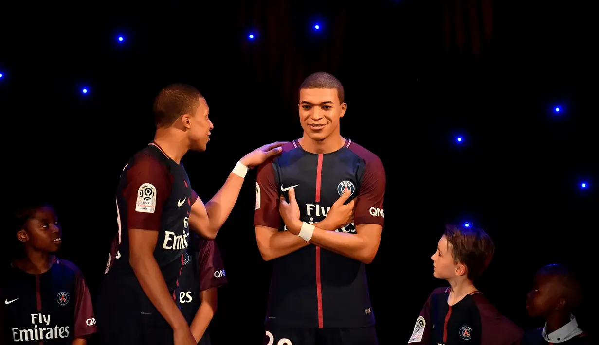 Striker PSG, Kylian Mbappe, memegang patung lilin rupa dirinya di Museum Grevin, Paris, Kamis (17/5/2018). Patung ini merupakan apresiasi karena keberhasilannya meraih gelar pemain muda terbaik dan trofi Liga Prancis. (AFP/Christophe Simon)