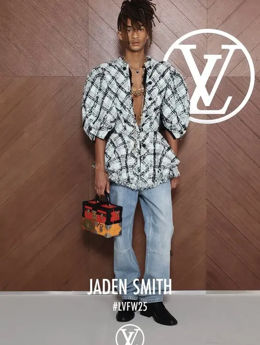 Jaden Smith hadir dengan atasan kemeja lengan balon motif kotak-kotak bergaris hitam dipadukan kalung layering dan celana denim panjang. Membawa tas kotak dan mengenakan sepatu pantofel berhak hitam. [dok. Louis Vuitton]