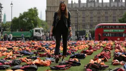 Seorang wanita berdiri di antara ribuan jaket pelampung para pengungsi, yang dipajang di dekat Gedung Parlemen London, Inggris, Senin (19/9). Aksi ini untuk memfokuskan KTT PBB tentang Mengatasi Gerakan Besar Pengungsi dan Migran. (Daniel Leal-Olivas/AFP)