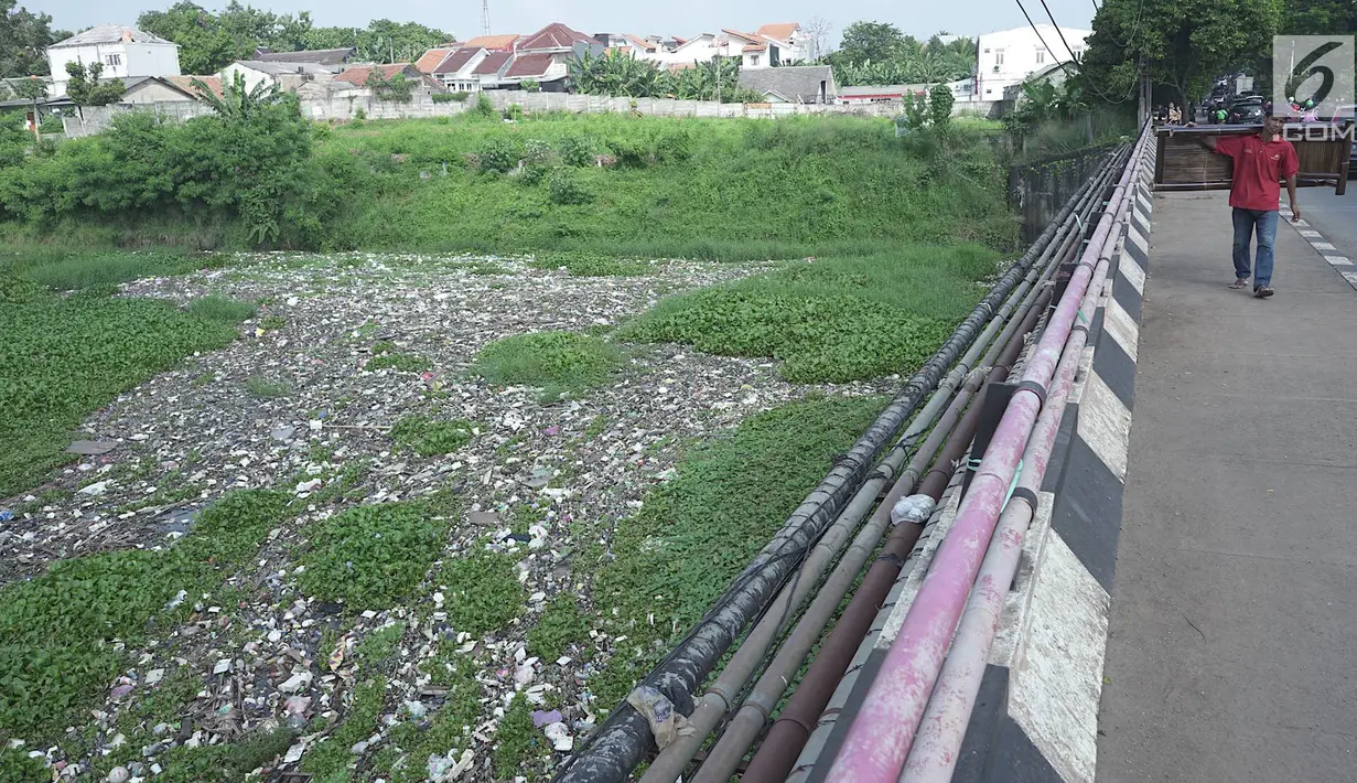 Warga berjalan melintasi Setu Pengarengan yang dipenuhi sampah dan eceng gondok di Depok, Jawa Barat, Selasa (7/5/2019). Keberadaan sampah dan eceng gondok di Setu Pengarengan menimbukan kesan kumuh. (Liputan6.com/Immanuel Antonius)