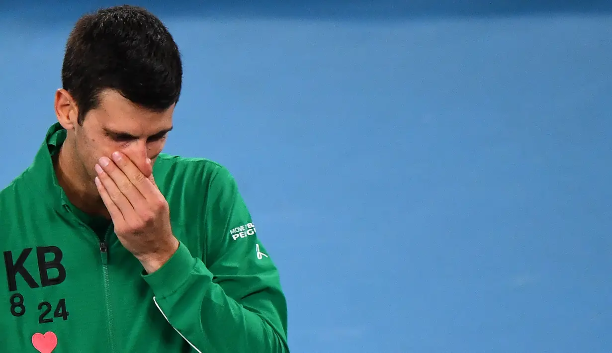 Petenis Serbia, Novak Djokovic, menangis saat diwawancara tentang Kobe Bryant seusai laga Australia Open 2020 di Melbourne, Selasa (28/1). Beri penghormatan dirinya memakai jaket inisial Kobe Bryant. (AFP/William West)