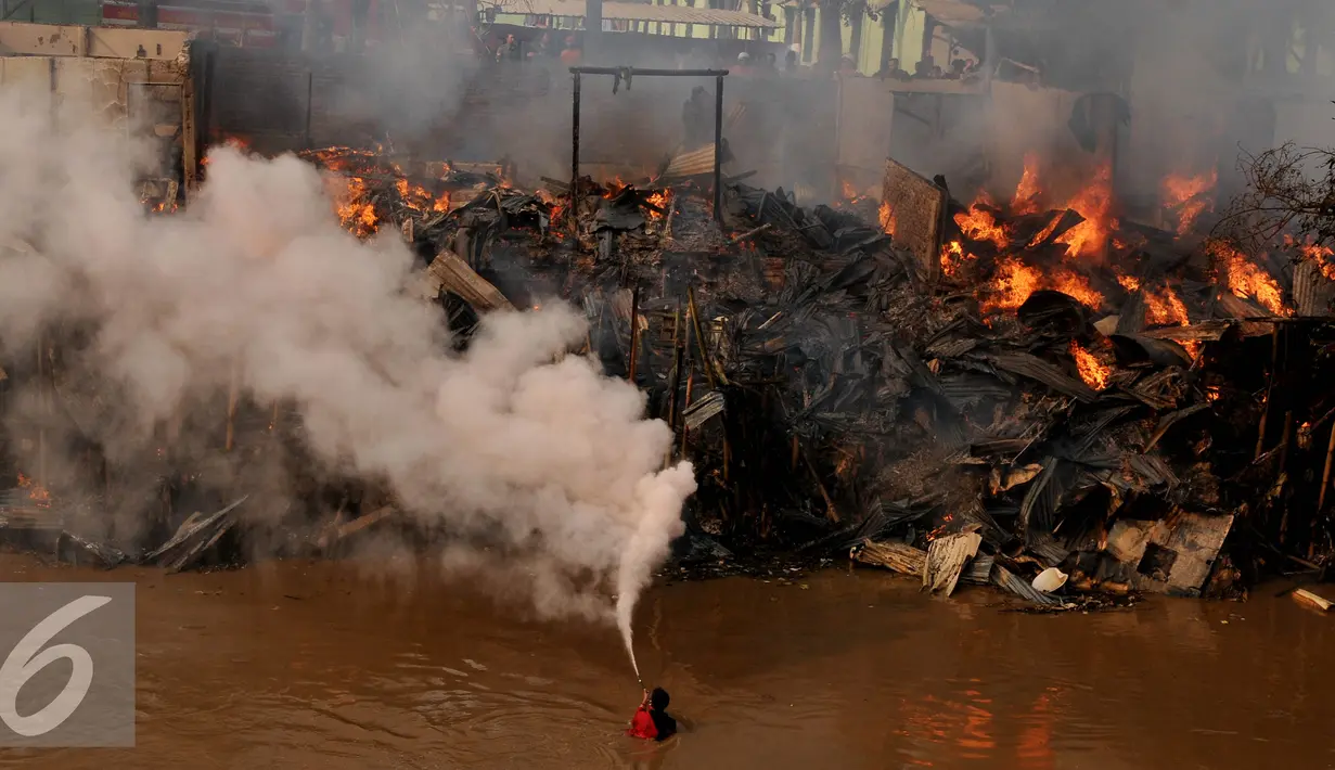 Seorang warga menyemprotkan alat pemadam api saat terjadinya kebakaran di bantaran sungai Ciliwung, Jakarta, Rabu (2/9/2015). Penyebab kebakaran tersebut belum di ketahui. (Liputan6.com/Johan Tallo)