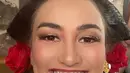 Wajahnya pun dipoles glamor dengan mengaplikasikan lipstik merah matte, bluson pink, daj riasan mata shimmer kecoklatan. Rambutnya ditata dengan sanggul klasik khas Jawa ditambah ornamen bunga mawar merah. [@atiqahhasiholan]