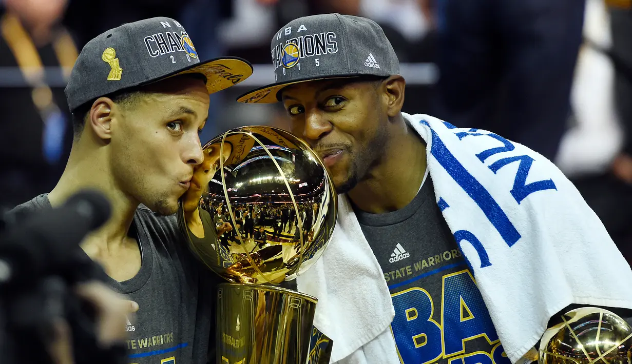 Stephen Curry (kiri) dan Andre Iguodala mencium trofi usai mengalahkan Cleveland Cavaliers di pertandingan ke enam final NBA di Quicken Loans Arena, (17/6/2015). Warriors menang 105-97 pada pertandingan ke enam final NBA. (Reuters/Bob Donnan)