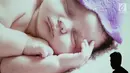 Seorang pria melintas di depan layar yang menunjukkan gambar bayi dalam acara pijat massal bayi di Gedung Kementerian Kesehatan, Jakarta, Selasa (7/11). Acara ini diikuti 300 bayi dan anak bawah dua tahun. (Liputan6.com/Immanuel Antonius)