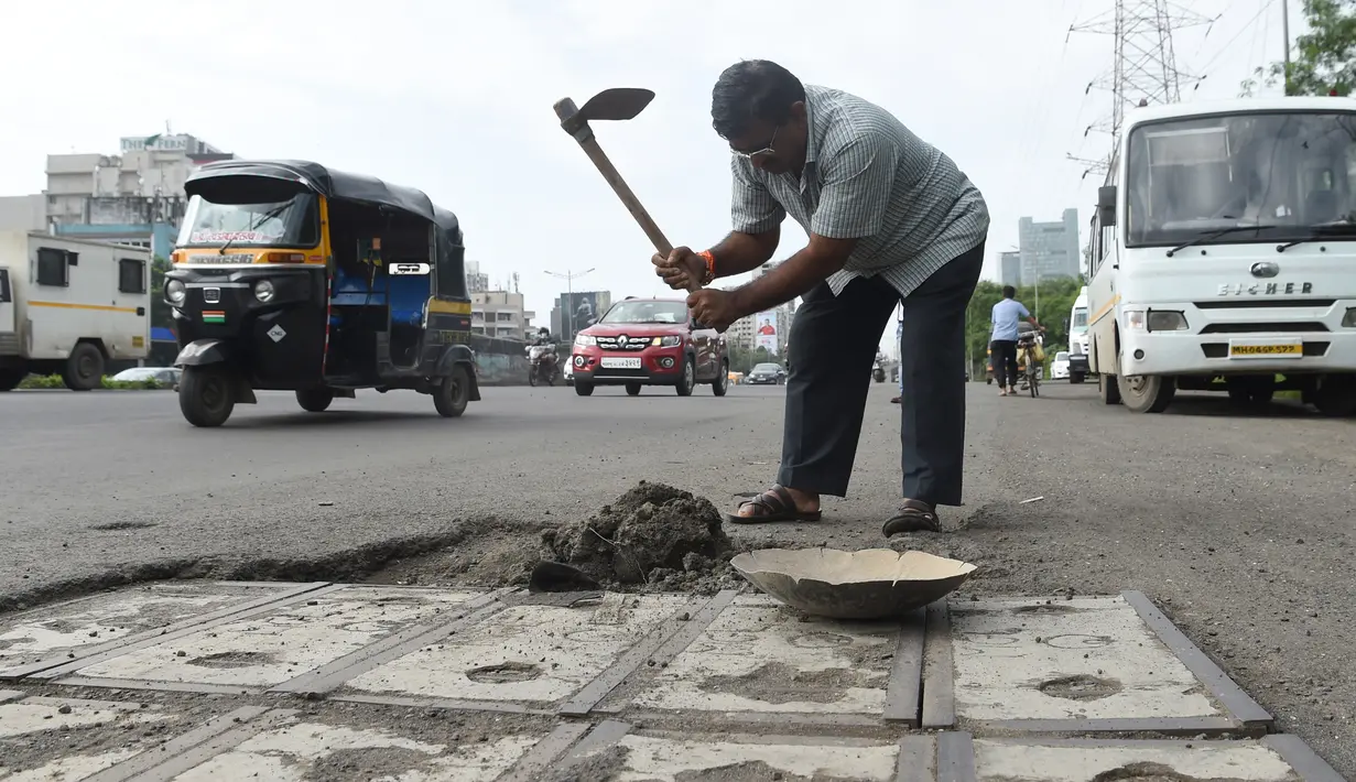 Foto pada 29 Agustus 2018, Dadarao Bilhore (48) menutup jalan yang berlubang di jalan raya Western Express, Mumbai. Ayah asal India itu mengobati kesedihannya dengan menutupi lubang di jalan raya serta meratakan jalanan yang rusa. (INDRANIL MUKHERJEE/AFP)