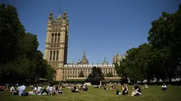 Orang-orang berbincang saat bersantai di bawah sinar matahari di Victoria Tower Gardens dekat Gedung Parlemen di London (23/7/2019). Suhu melonjak di atas 30C (86F) di Inggris pada 23 Juli dengan para peramal cuaca memperkirakan suhu setinggi 37C (96.8F) sebelum akhir pekan. (AFP Photo/Ben Stansall)