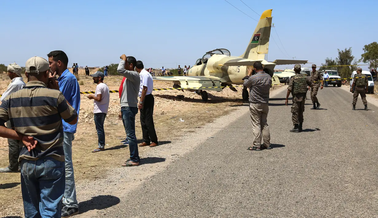 Sejumlah warga melihat kondisi pesawat jet tempur Libya L-39 Albatros pasukan Khalifa Haftar di Kota Medenine di perbatasan Tunisia-Libya (22/7/2019). Jet tempur tersebut mendarat di jalan raya. (AFP Photo/Fathi Nasri)