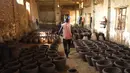 Seorang perajin Sudan berjalan melewati sejumlah tembikar di Khartoum, Sudan (20/10/2020). Para perajin tembikar di Sudan memanfaatkan tanah liat sisa banjir untuk membuat benda-benda kerajinan tersebut. (Xinhua/Mohamed Khidir)